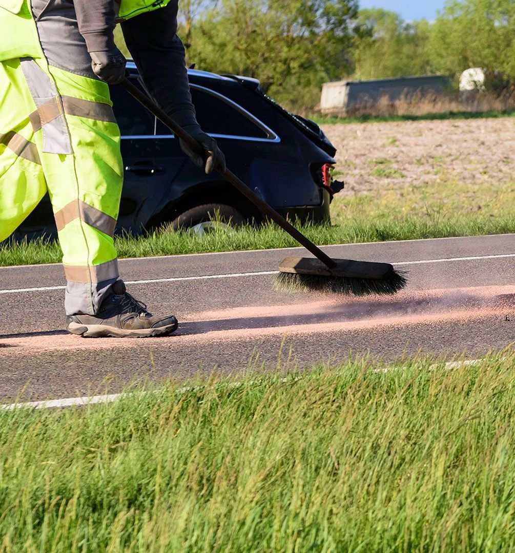 Oil is being removed from the road with a broom.