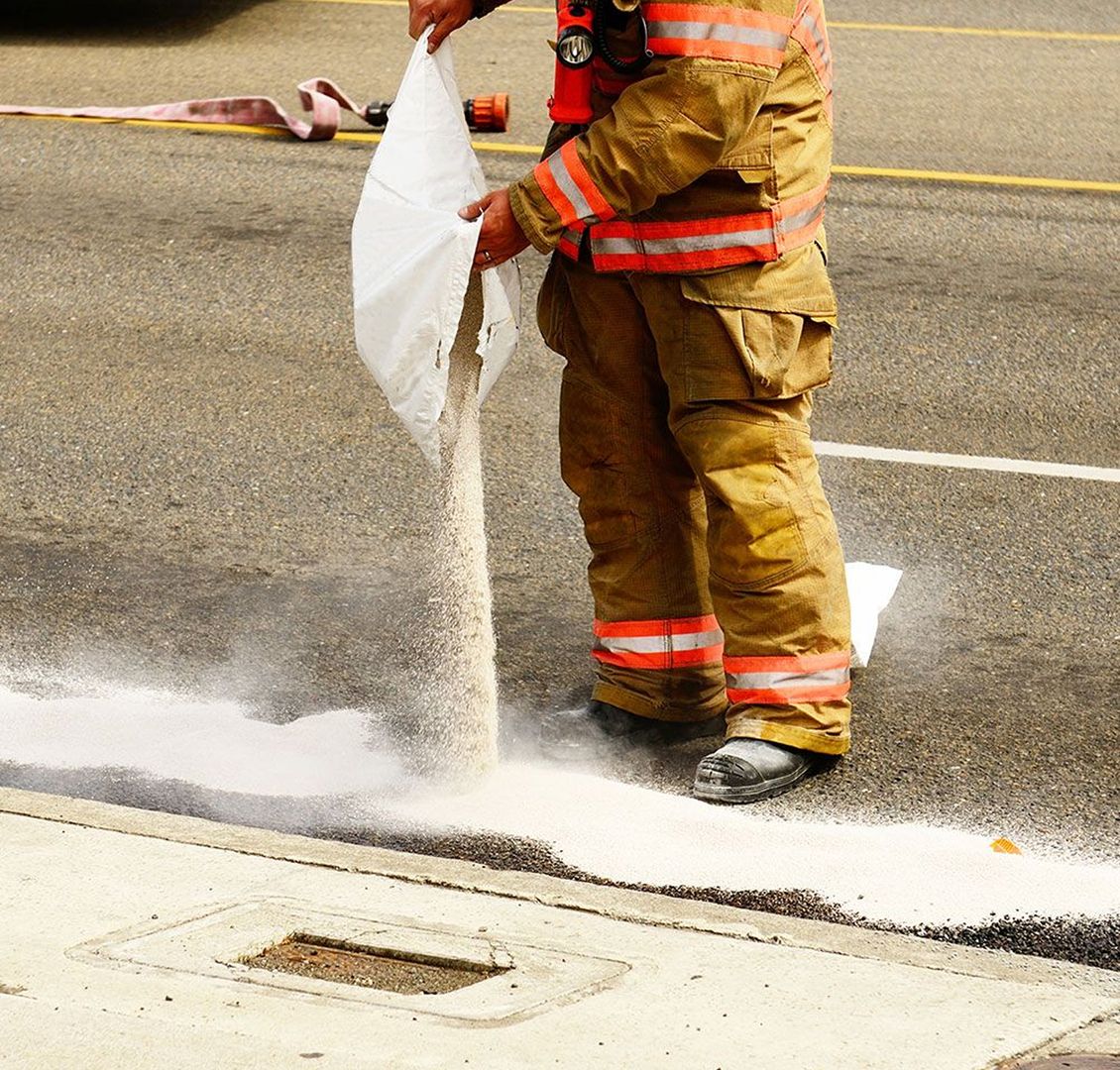 Oil absorbent is being spread on a road.