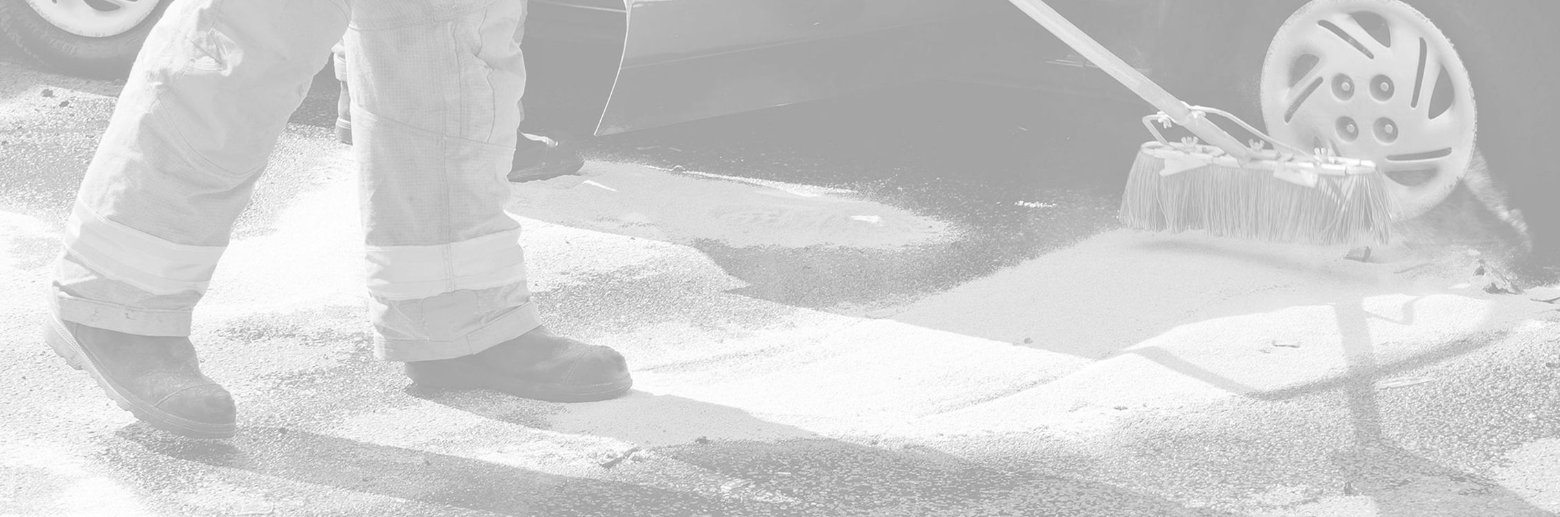 Ölbindemittel wird auf einer Straße mit einem Besen verteilt